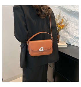 Detail view of the silver heart-shaped metal buckle on a retro leather underarm bag