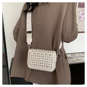 Close-up of cream PU crossbody bag with silver studs and patterned wide shoulder strap
