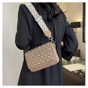 Detail view of stylish apricot PU shoulder bag with silver studs and patterned wide strap