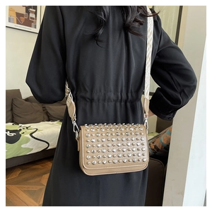 Detail of light beige PU leather bag with silver rivets and geometric woven strap
