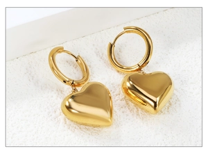 Détails macro des breloques cœur en or 18 carats sur créoles polies pour femme
