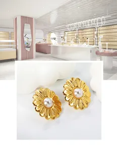 Detail of gold daisy earrings with central white pearl on a decorative white cloud prop