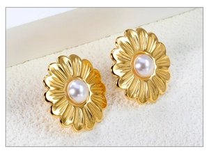 Detailed close-up of 18K gold-plated flower earrings with center pearls on a white surface