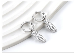Artistic silver hoop earrings with abstract female torso charms on white stone base