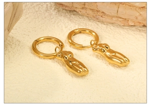Artistic gold female body sculpture earrings shown on natural stone background