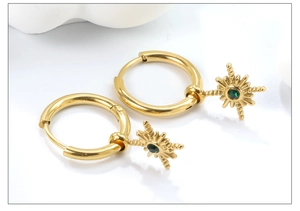 Detailed macro view of gold-plated starburst earrings with green gemstone inlay