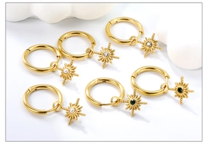 Close-up of gold North Star hoop earrings with crystals, pearls, and green gemstones