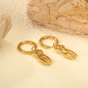 Artistic gold female silhouette hoop earrings on natural stone background with macro detail
