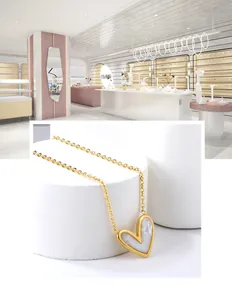 Dettaglio di una collana dorata con pendente a cuore in madreperla bianca su base