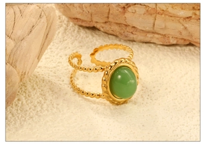 Vue macro d'une bague dorée ajustable avec un cabochon vert ovale et bordure perlée