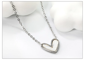 Dettaglio macro del ciondolo a cuore con inserto in madreperla e catena in argento