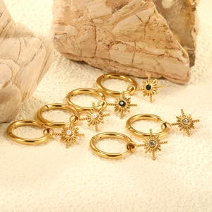 Three pairs of gold north star hoop earrings with pearl, green gem, and clear crystals