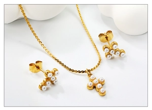 Vue détaillée du collier pendentif croix et boucles d'oreilles perles sur décor blanc