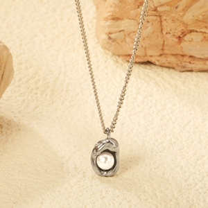 Collana con ciondolo a fiocco d'argento e perla irregolare su sfondo in pietra materica