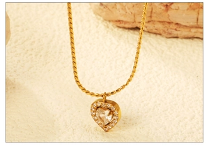 Close-up of gold heart necklace with sparkling zircon pendant on a twisted rope chain