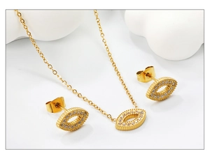 Detail of gold jewelry set with eye-shaped necklace and earrings encrusted with zircon