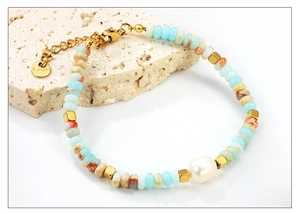 Detail of colorful beads with large pearl and gold stainless steel clasp on stone
