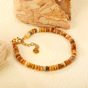 Colorful natural stone bead bracelet with stainless steel gold clasp on a rock background