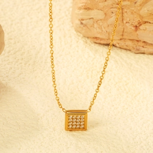 Minimalist gold square pendant necklace with inlaid crystals on white textured surface