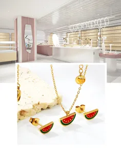 Close-up of enamel watermelon jewelry set including gold necklace and stud earrings