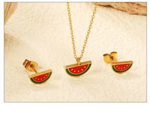 Detailed view of gold watermelon enamel necklace and stud earrings set on a textured surface
