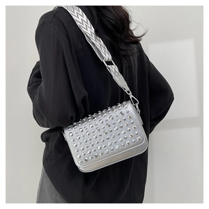 Detail of silver crossbody bag with sparkling rhinestones and black-white herringbone strap