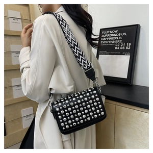 Detail of black PU shoulder bag with silver studs and geometric patterned wide strap
