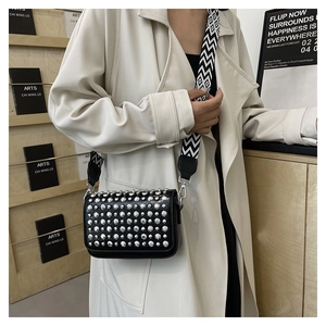 Detail of black PU crossbody bag with silver studs and a geometric woven strap
