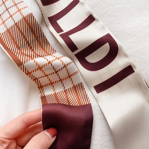 Détail en gros plan d'un foulard en satin étroit avec motif à carreaux et imprimé