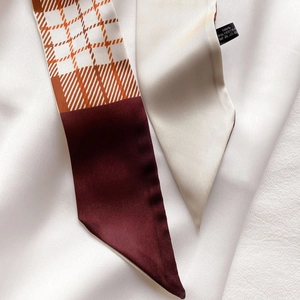 Gros plan montrant la texture diagonale soyeuse et le motif à carreaux du foulard 100% polyester