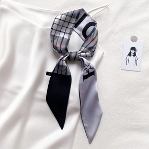 Gros plan sur un foulard étroit en soie à carreaux avec logo H et étiquette de marque