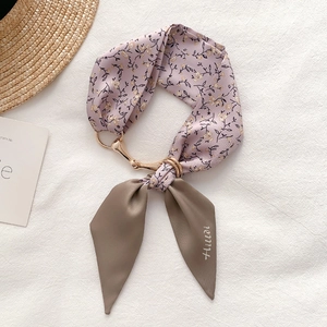 Macro view of floral pattern scarf with golden horsebit buckle on textured fabric