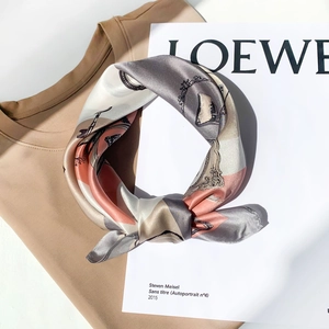 Detailed texture of geometric silk scarf knotted over a knitted sweater and magazine