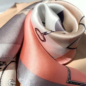 Detailed macro view of the folded silk scarf showing premium satin texture and equestrian print