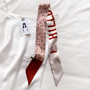 Détail d'un foulard étroit en soie à carreaux avec texte HILL sur un haut en soie