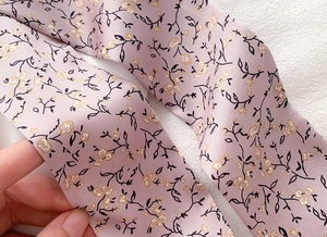 Detail of floral silk scarf showing delicate yellow flowers and satin fabric texture