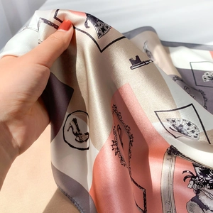Detailed close-up of hand-held silk scarf featuring elegant geometric patterns and art prints