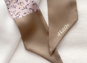 Close-up of floral print and khaki patchwork silk scarf with brand logo text