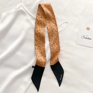 Detail of floral twilly scarf with ginger base, black leaf pattern and contrast tip