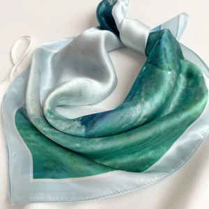 Detailed view of silk scarf texture showing smooth blue and green marble pattern