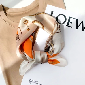 Detail of silk scarf with orange and beige vintage key prints on a beige shirt