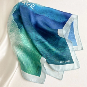 Detail shot of silk square scarf featuring ocean wave patterns and premium smooth texture