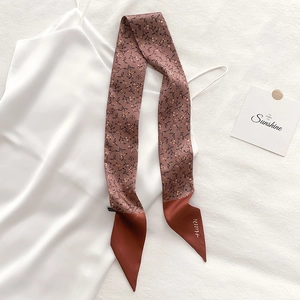 Floral skinny scarf with pink flower pattern draped over a white satin dress