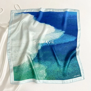 Close-up of a silk square scarf featuring a blue sea wave gradient print and smooth texture