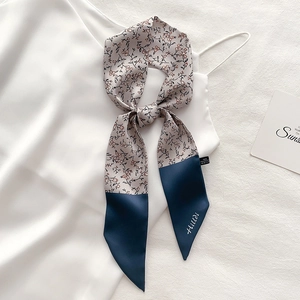 Floral skinny scarf and ribbon accessory tied on white silk dress in a soft layout