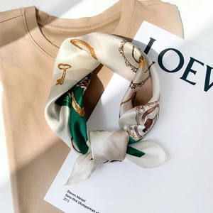 Silk scarf detail showing emerald green gold key patterns tied on beige cotton shirt