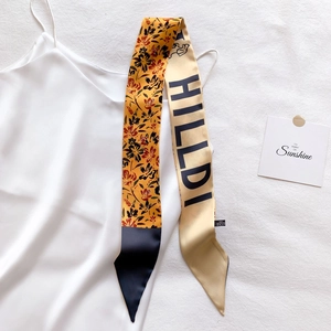 Détail d'un foulard twilly en polyester sur top en soie avec imprimé floral élégant