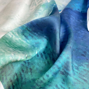 Detailed macro shot of blue silk scarf fabric showing smooth texture and abstract print