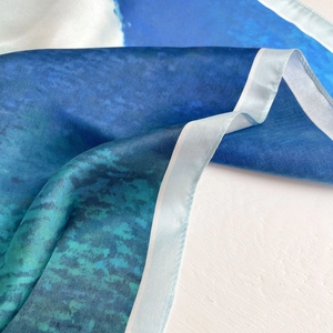 Close-up of silk scarf showing smooth texture and light blue gradient watercolor patterns