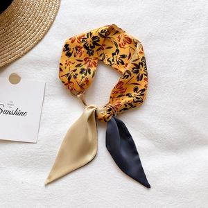 Détail d'un foulard étroit à imprimé fleuri jaune avec boucle de connexion en métal